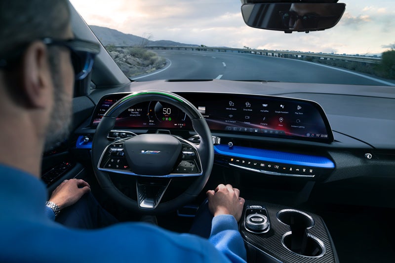 Front View of the 2026 OPTIQ-V Driving Through the Dusk Utilizing its Headlights | Graham Cadillac in MANSFIELD OH