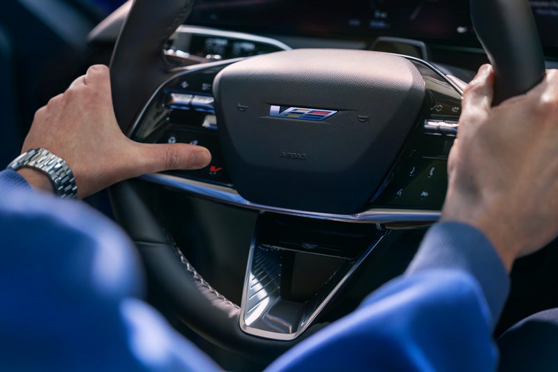 Close-up of a Man About to Press the V-Button on the 2026 OPTIQ-V Steering Wheel | Graham Cadillac in MANSFIELD OH